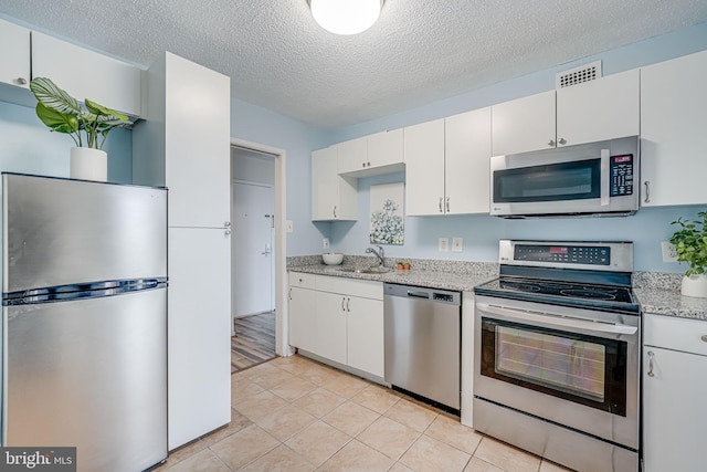 2311 Pimmit Dr Unit 1102, Falls Church, VA 22043 - kitchen featuring appliances with stainless steel finishes, a sink, white cabinetry, a textured ceiling, and light tile patterned floors