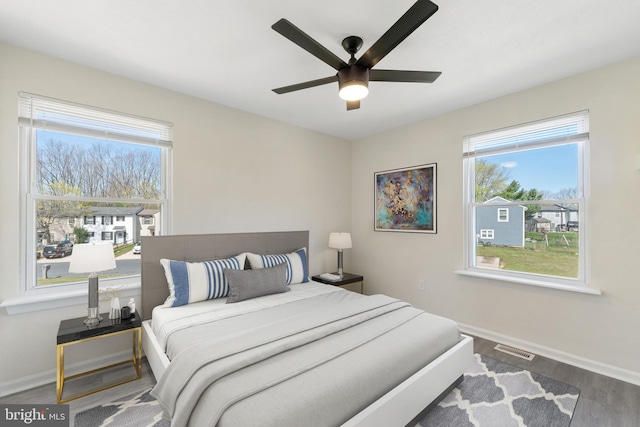 bedroom with wood finished floors, ceiling fan, baseboards, and visible vents