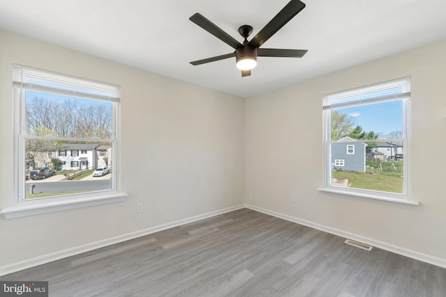 spare room with visible vents, baseboards, a ceiling fan, and wood finished floors