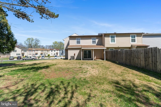 rear view of house featuring cooling unit, fence, and a lawn