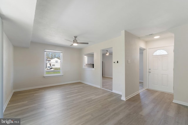 interior space featuring ceiling fan, light wood finished floors, and baseboards