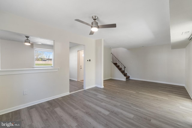 interior space with baseboards, stairs, visible vents, ceiling fan, and wood finished floors