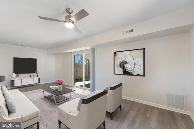 living area with visible vents, baseboards, a ceiling fan, and wood finished floors