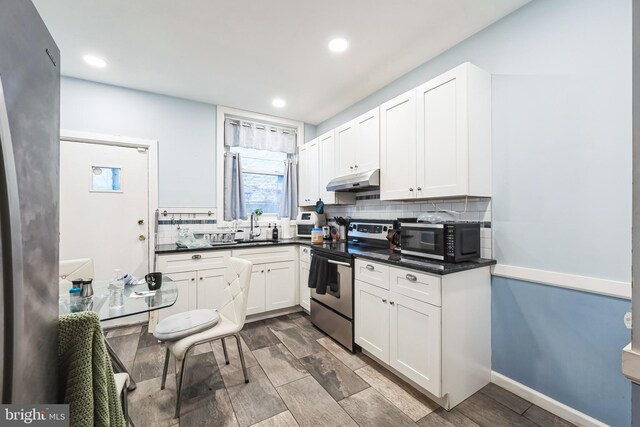 4910 N Hutchinson St, Philadelphia, PA 19141 - kitchen with tasteful backsplash, a sink, dark countertops, electric stove, and under cabinet range hood