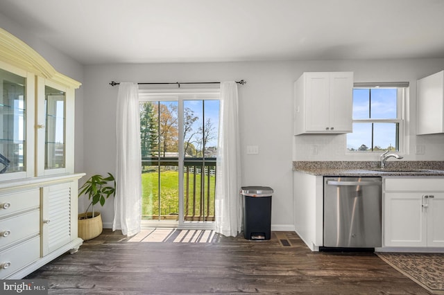 kitchen with stainless steel dishwasher, a sink, light stone countertops, and dark wood-style flooring