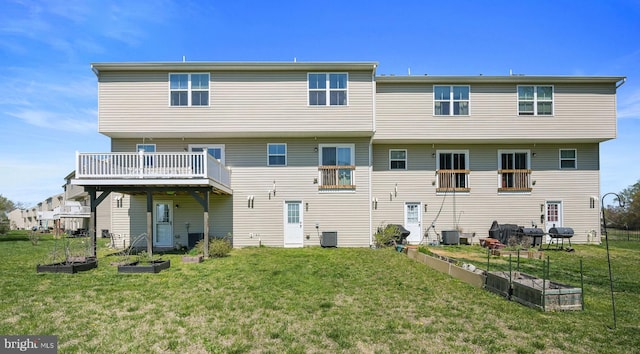 rear view of house with a yard, a vegetable garden, and central air condition unit
