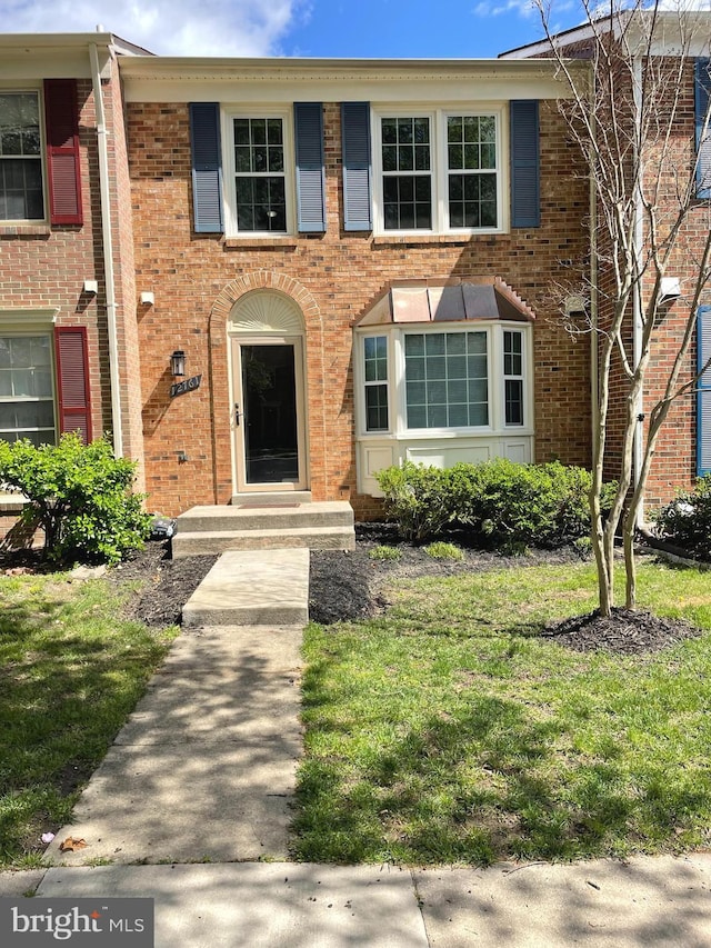 view of property featuring brick siding and a front lawn