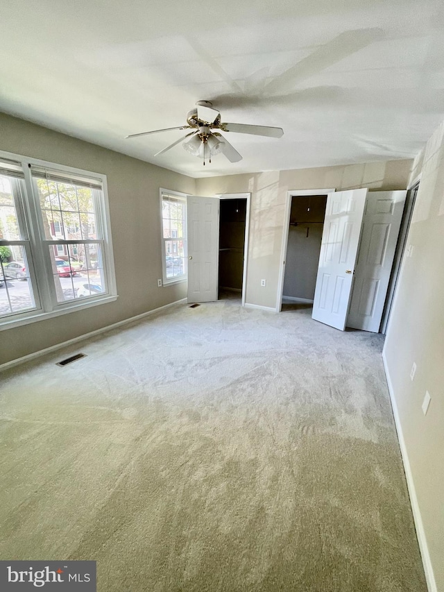 unfurnished bedroom with ceiling fan, carpet floors, two closets, baseboards, and visible vents