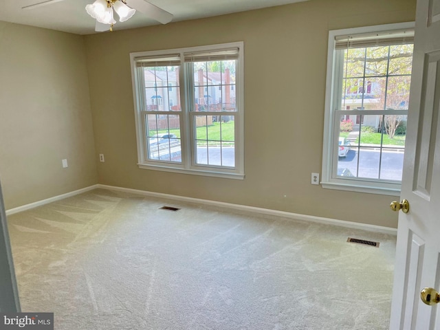 carpeted empty room featuring baseboards, visible vents, and a healthy amount of sunlight