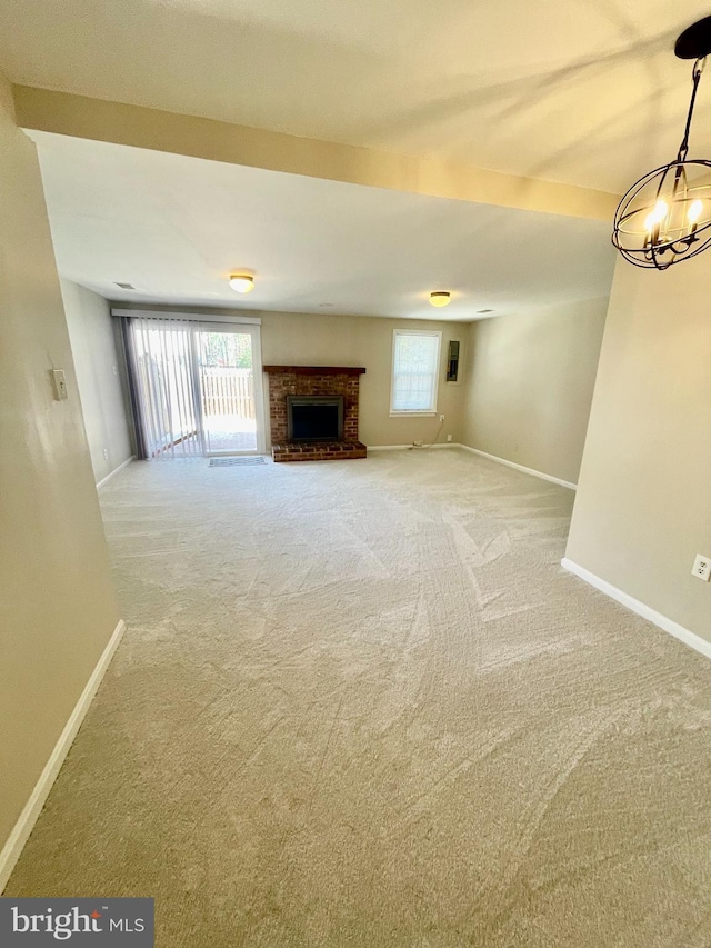unfurnished living room with carpet floors, baseboards, a fireplace, and a notable chandelier