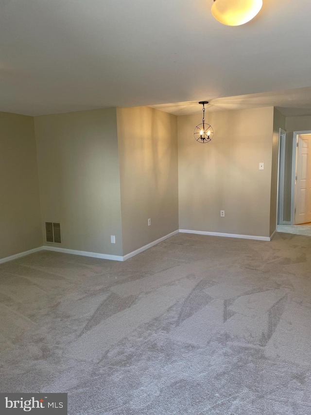 empty room with visible vents, carpet flooring, baseboards, and a notable chandelier
