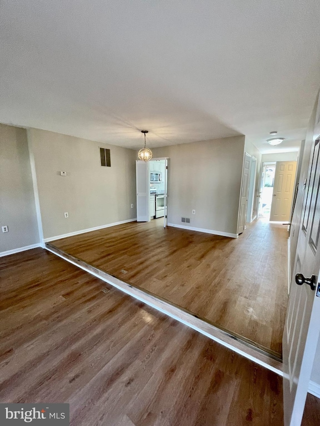 unfurnished dining area with baseboards, wood finished floors, and visible vents