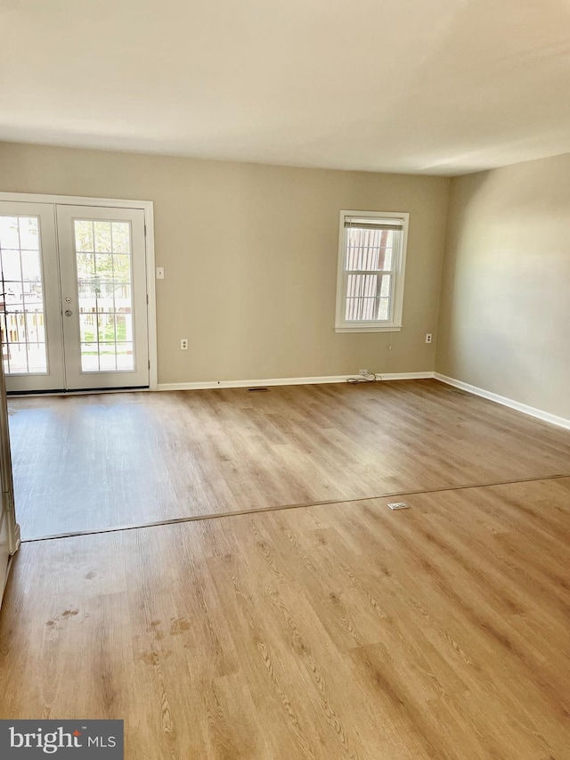 unfurnished room with baseboards, french doors, and wood finished floors