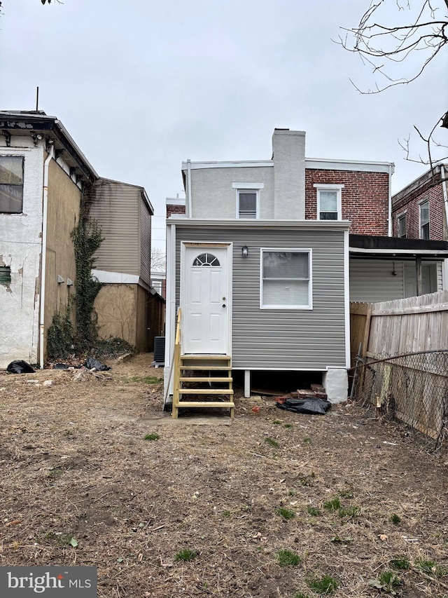 back of house featuring entry steps, fence, and central AC unit