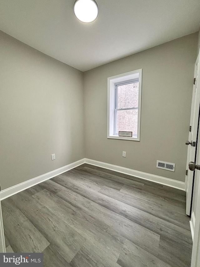 spare room with dark wood-style flooring, baseboards, and visible vents