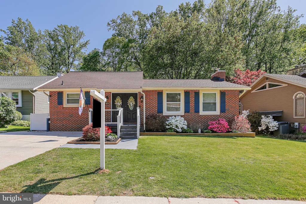 ranch-style house featuring central AC, a front yard, a chimney, brick siding, and concrete driveway