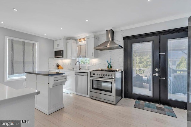 kitchen with french doors, backsplash, crown molding, wall chimney exhaust hood, and stainless steel appliances