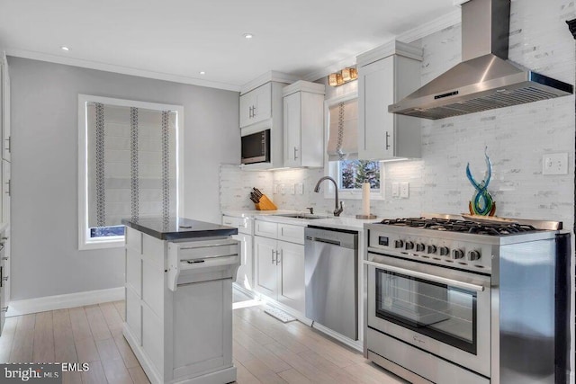 kitchen with stainless steel appliances, wall chimney exhaust hood, a sink, and decorative backsplash