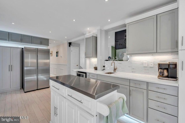 kitchen with ornamental molding, a sink, stainless steel fridge, gray cabinetry, and backsplash