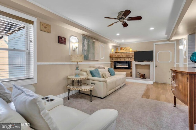 living room with a stone fireplace, recessed lighting, carpet flooring, a ceiling fan, and crown molding
