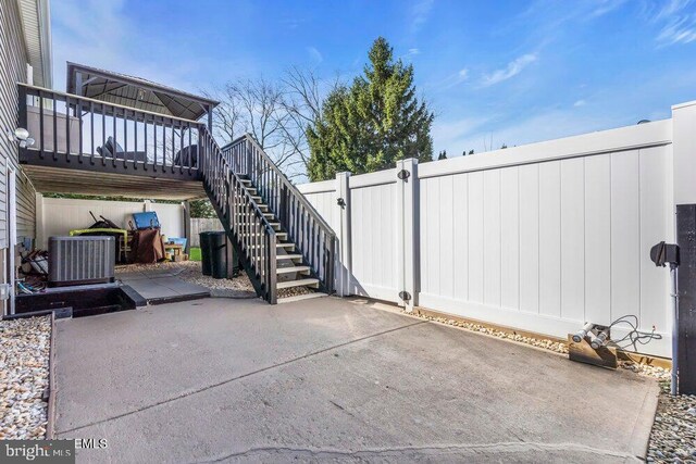 view of patio with central AC, fence, and stairs