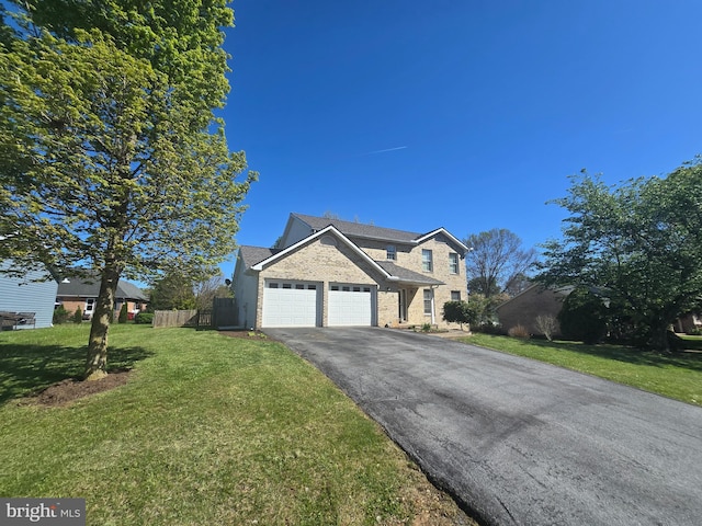 traditional-style house with aphalt driveway, fence, a front yard, brick siding, and an attached garage