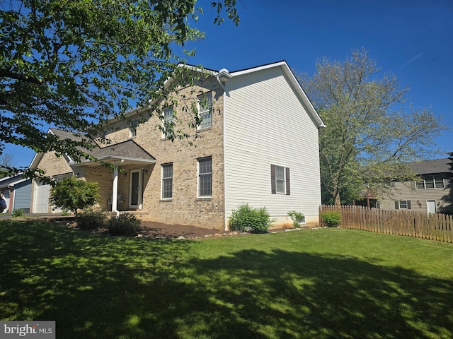 view of home's exterior featuring fence, a yard, a garage, and brick siding