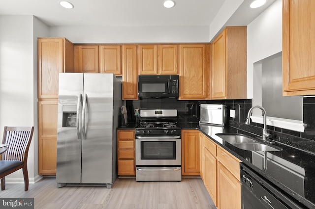 kitchen featuring light wood finished floors, a sink, recessed lighting, and appliances with stainless steel finishes