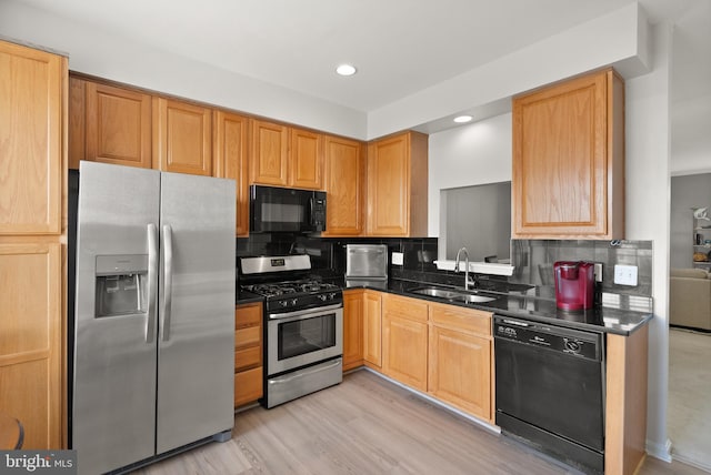 kitchen featuring recessed lighting, dark countertops, a sink, decorative backsplash, and black appliances
