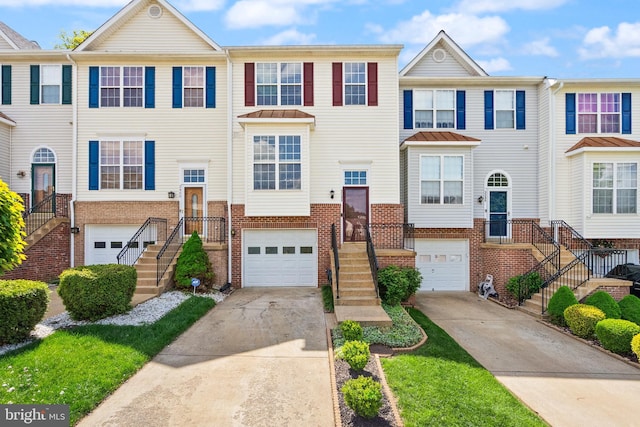 townhome / multi-family property with a garage, driveway, and brick siding