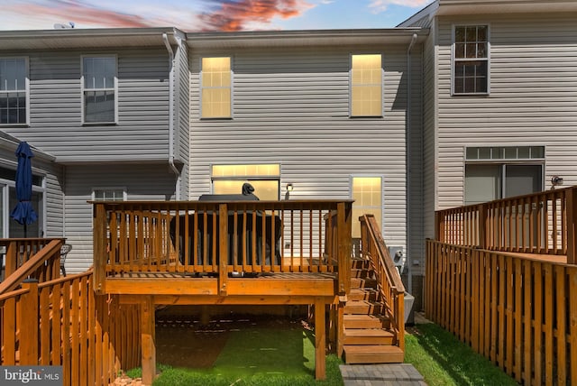 back of house at dusk featuring stairway and a wooden deck