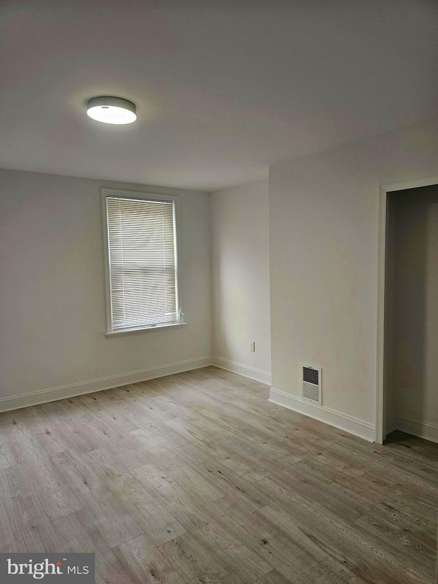 spare room with wood finished floors, baseboards, and visible vents
