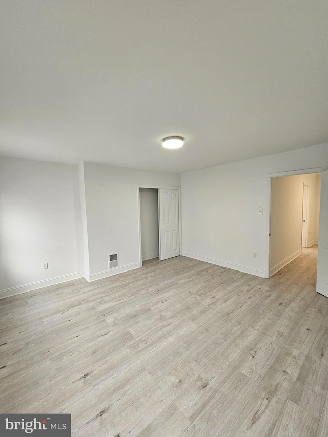 empty room featuring light wood-style flooring, baseboards, and visible vents