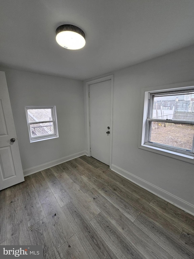 spare room with a wealth of natural light, baseboards, and wood finished floors