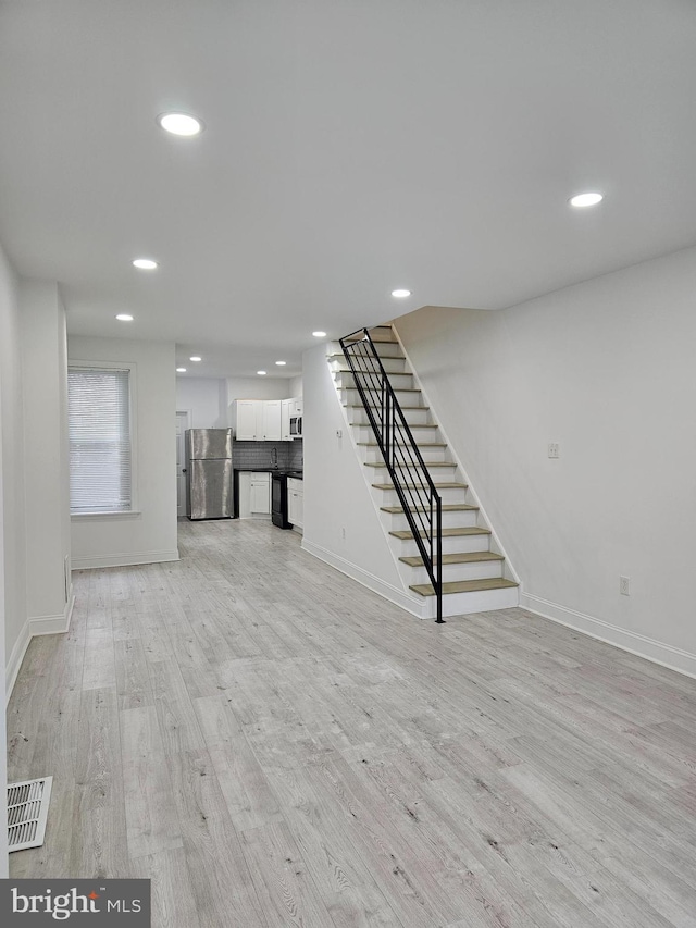 unfurnished living room with baseboards, recessed lighting, stairs, light wood-style floors, and visible vents