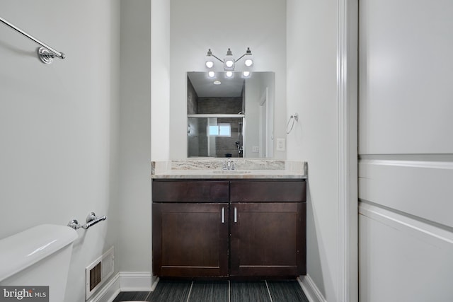 full bathroom featuring vanity, baseboards, a stall shower, toilet, and visible vents