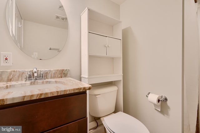 bathroom featuring toilet, vanity, and visible vents