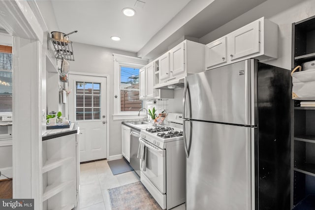kitchen featuring light tile patterned floors, white cabinets, a sink, recessed lighting, and stainless steel appliances