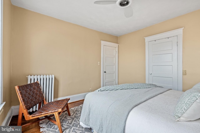bedroom featuring wood finished floors, radiator heating unit, baseboards, and a ceiling fan