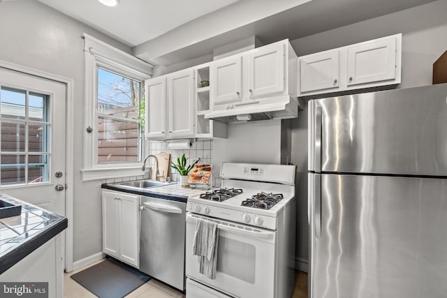 kitchen featuring stainless steel appliances, under cabinet range hood, tile countertops, and white cabinetry