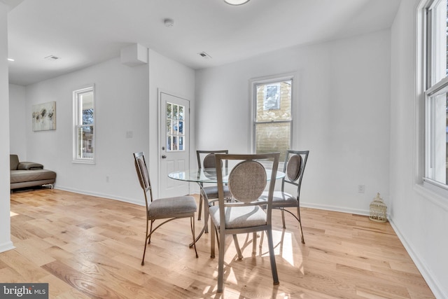 dining space featuring visible vents, light wood-style flooring, and baseboards