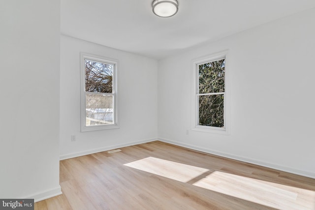 unfurnished room featuring visible vents, light wood-style flooring, and baseboards