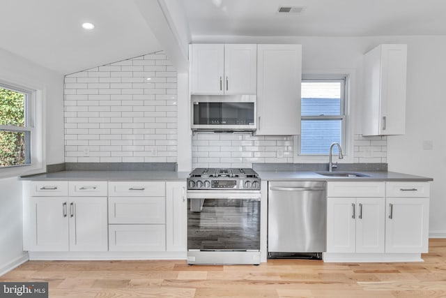 kitchen with visible vents, a sink, white cabinetry, backsplash, and appliances with stainless steel finishes