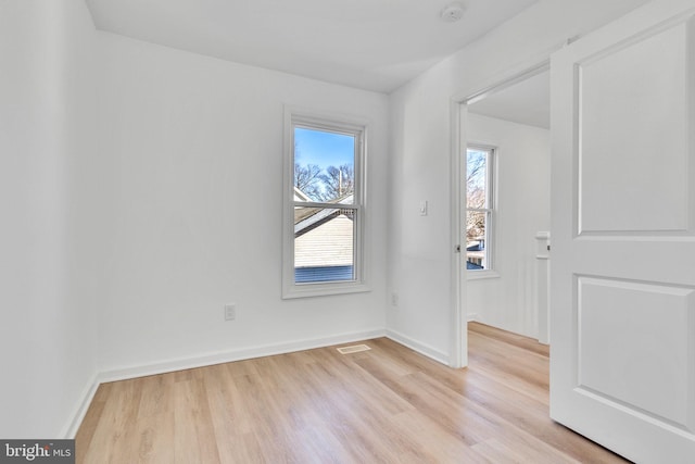 spare room featuring baseboards, light wood finished floors, and visible vents