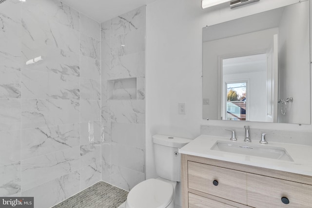 bathroom featuring vanity, toilet, and a tile shower