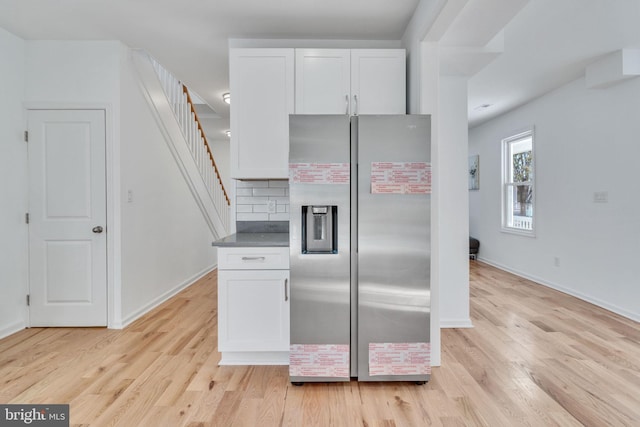 kitchen featuring light wood-type flooring, tasteful backsplash, stainless steel refrigerator with ice dispenser, and white cabinets