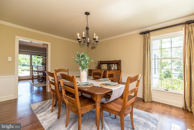 dining area featuring a chandelier, crown molding, plenty of natural light, wood finished floors, and baseboards