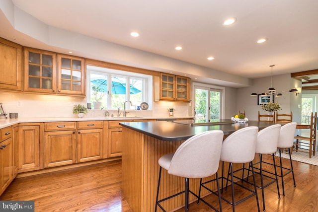 kitchen with a sink, light wood-style floors, recessed lighting, backsplash, and a center island
