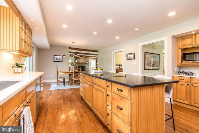 kitchen featuring stainless steel appliances, backsplash, a breakfast bar area, recessed lighting, and wood finished floors