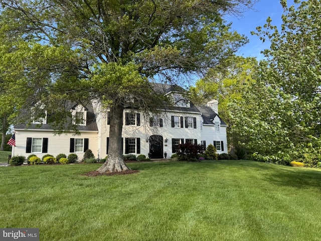 view of front facade featuring a front lawn and a chimney